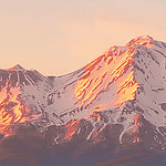 Снежная вершина горы в лучах вечернего розового солнца